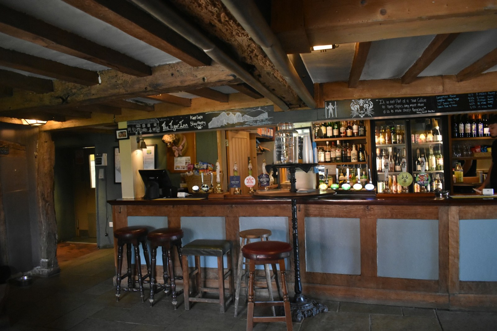 An empty British pub interior with bar stools and low beams, before opening.